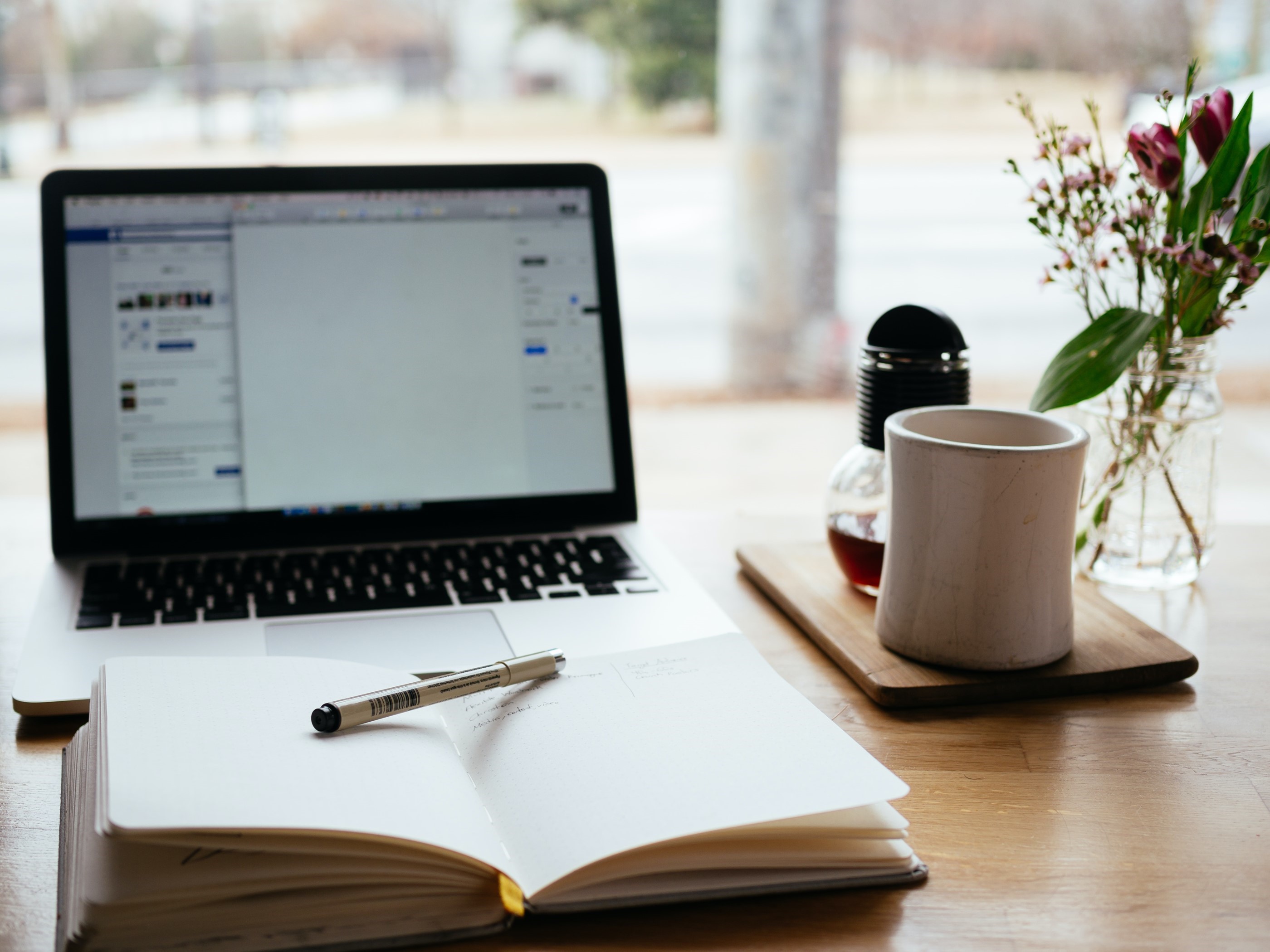 Desk with computer, open book and a coffee cup