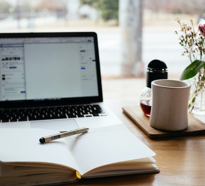 Desk with computer, open book and a coffee cup