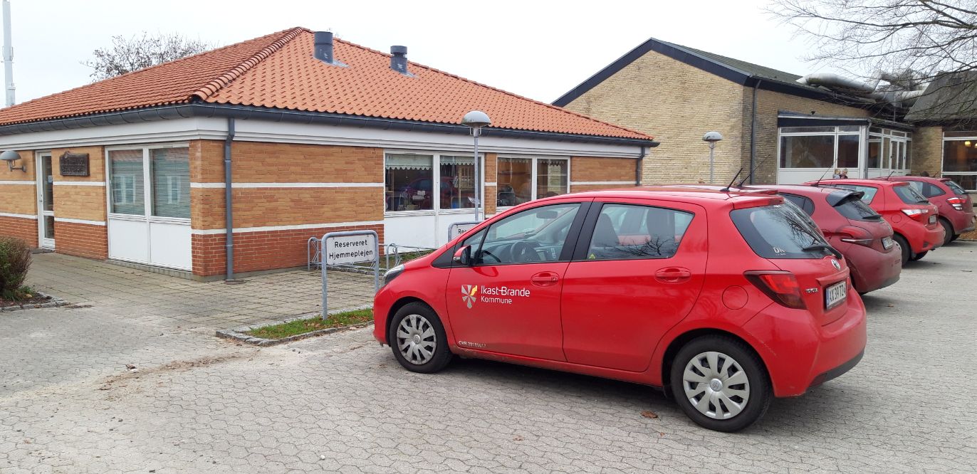 Hjemmeplejebiler ved siden af værkstedsbygning ved Frisenborg