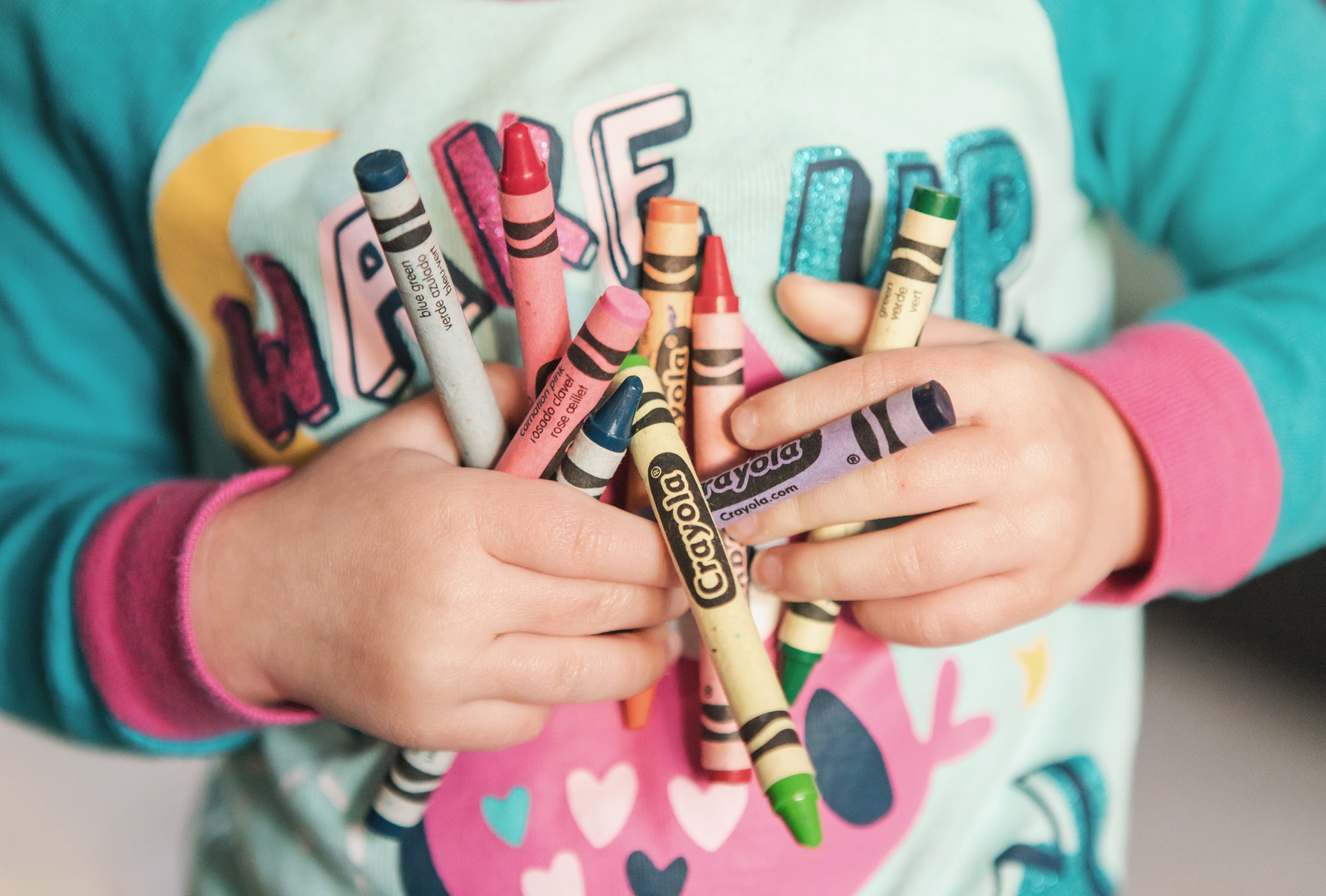Close-up of child holding crayons