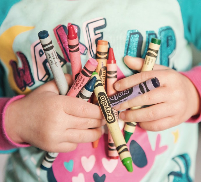 Close-up of child holding crayons
